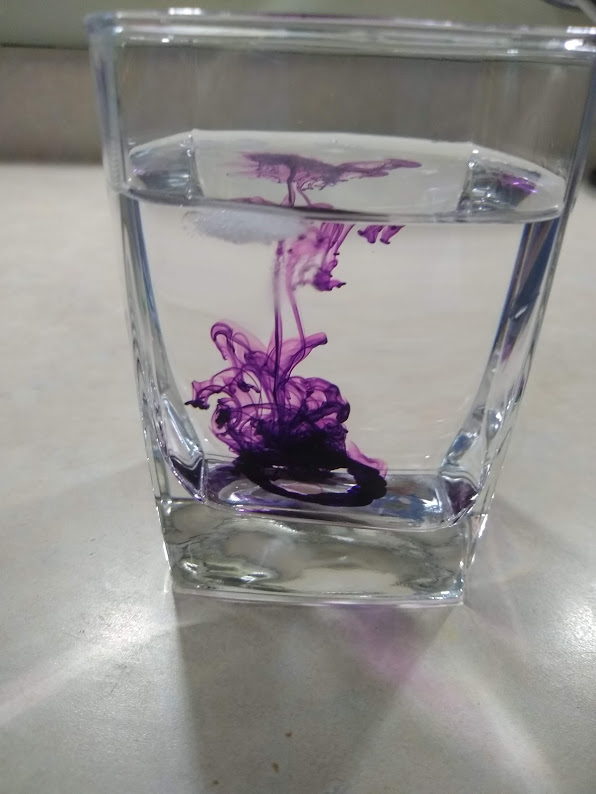Image of purple food dye in ice water, food dye settling at the bottom of the glass.